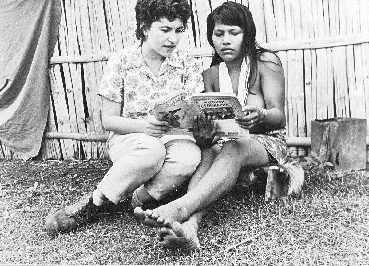 Reina Torres de Araúz reading National Geographic with an Indian woman of the Darién during the Trans-Darién Expedition. Photograph by Amado Araúz.