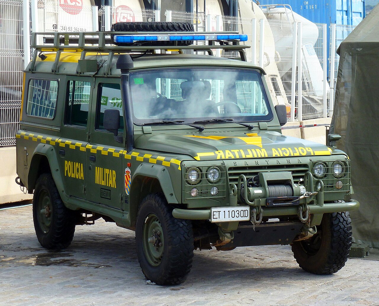 Policía Militar Aníbal — Military police Aníbal station wagon of the Unidad Militar de Emergencias (BIEM I), ET 110300 — yellow 'POLICIA MILITAR' lettering, chequered waist flash and blue light bar. A station wagon rather than the soft top