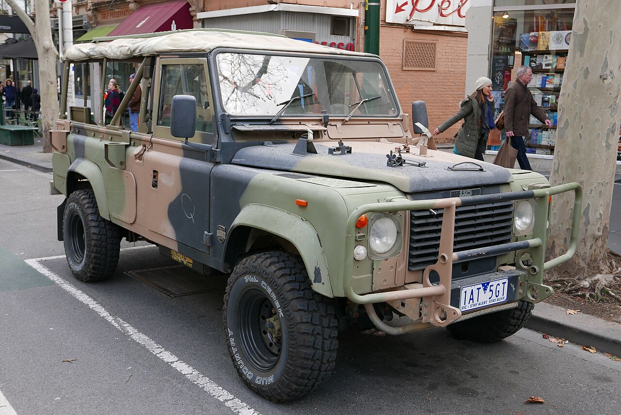 A 1990 ex-Australian Army Perentie 110 in Auscam disruptive-pattern camouflage on the street in Melbourne, 2015, with the canvas top run forward over the cab. The uploader labelled it a '110 County'; it is a Perentie, and the sides have been opened up in the way surplus owners commonly do.